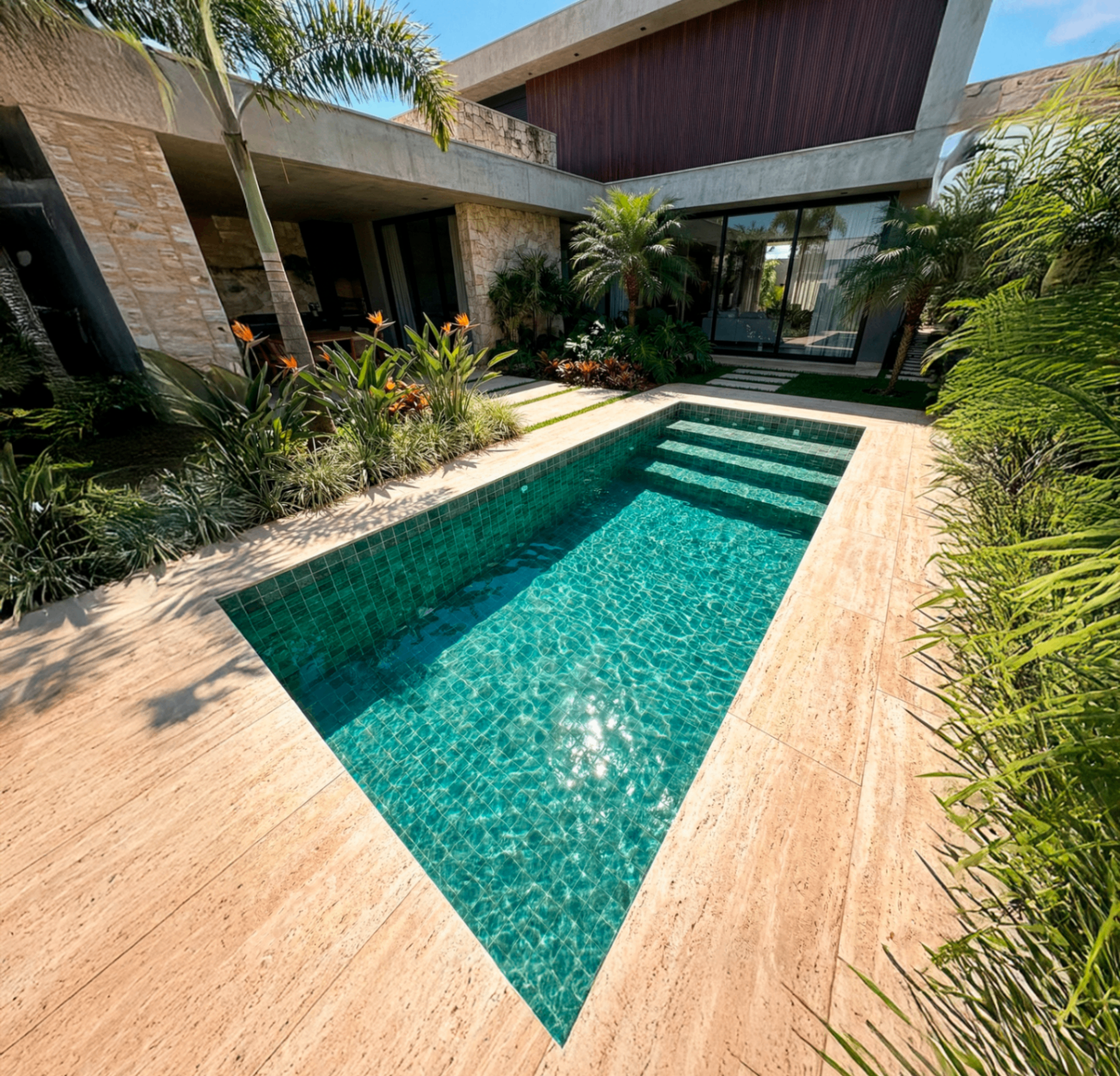 Piscina pastilhada verde em residência moderna com deck de pedra