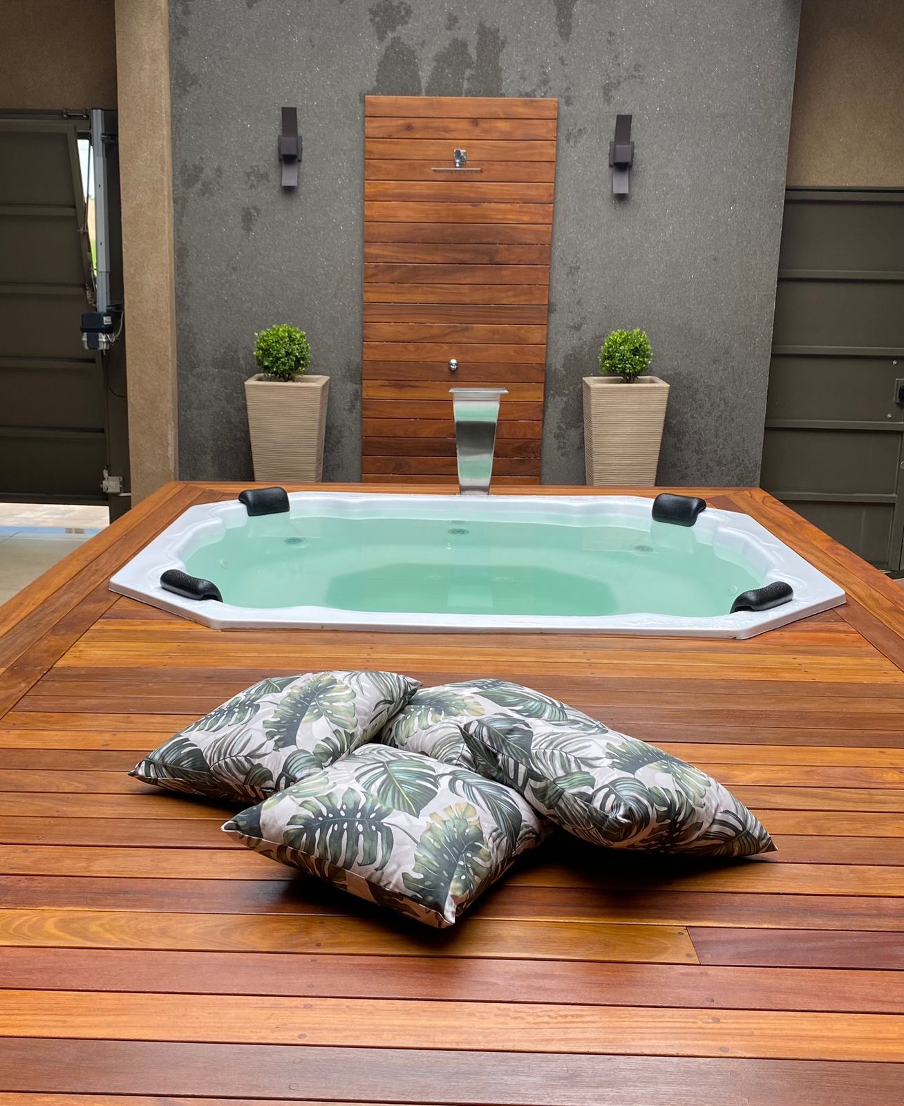 Spa com deck de madeira, cascata e almofadas tropicais