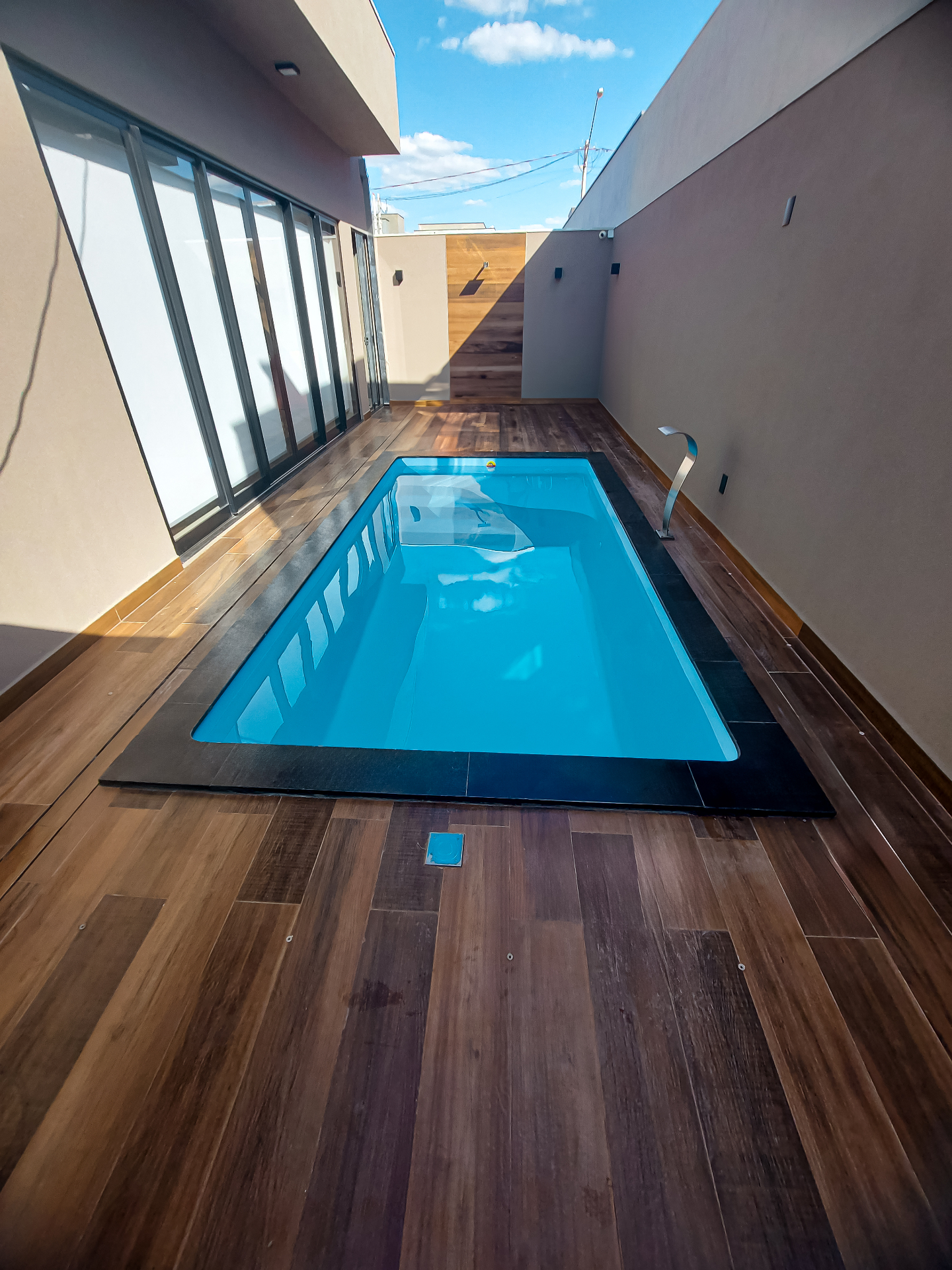 Piscina estreita em corredor externo com revestimento amadeirado